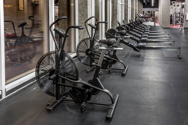 Exercício bicicletas, máquinas de remo e esteiras por janela em espaçoso, vazio ginásio interior. Equipamento especial para treinamento físico. Desporto, fitness — Fotografia de Stock
