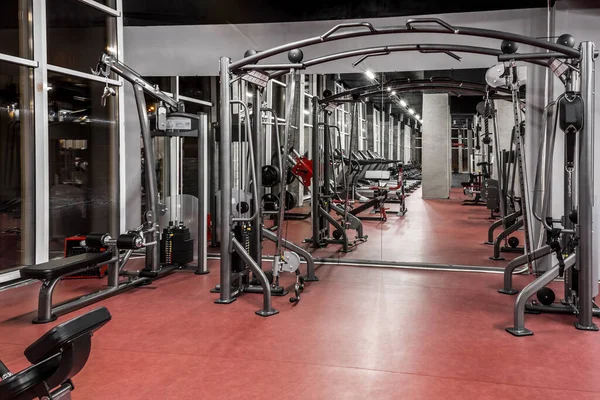 Máquinas de exercício para treinamento físico em espaçoso, bem iluminado, vazio ginásio interior com espelho enorme. Equipamento especial moderno. Desporto, fitness — Fotografia de Stock