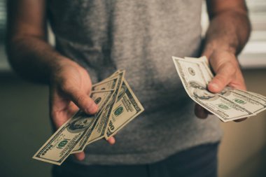 Bir adam dolar elinde tutar.