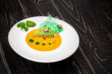 Siyah ahşap zemin üzerinde balkabağı çorbası olan bir kase. Şeften sağlam bir yem.