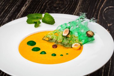 Siyah ahşap zemin üzerinde balkabağı çorbası olan bir kase. Şeften sağlam bir yem.