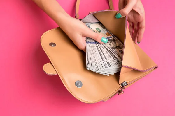 Kobiecy ręka usuwając pieniądze z małej torby, studio shot — Zdjęcie stockowe
