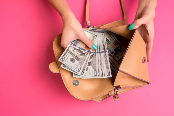 Kobiecy ręka usuwając pieniądze z małej torby, studio shot — Zdjęcie stockowe