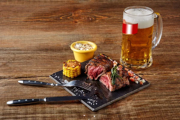 Grilovaná svíčková Steak roastbeef a houbová omáčka na černé řezací desce a sklenice piva na dřevěném pozadí — Stock fotografie