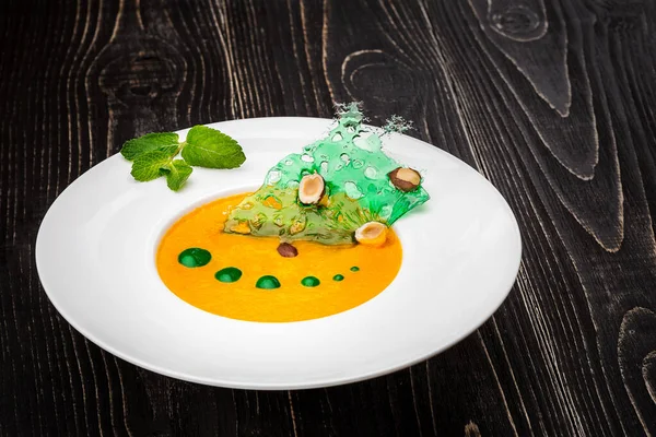 Siyah ahşap zemin üzerinde balkabağı çorbası olan bir kase. Şeften sağlam bir yem.