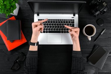 Ofis Masaları çalışan kadın. Ahşap masa arka plan üzerinde insan eli, laptop klavye, bir fincan kahve, smartphone, dizüstü bilgisayar ve bir çiçek Üstten Görünüm