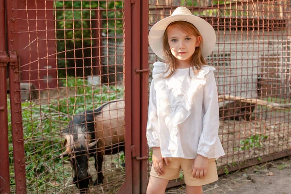 Девочка-подросток стоит возле ларька с козой на даче летом — стоковое фото