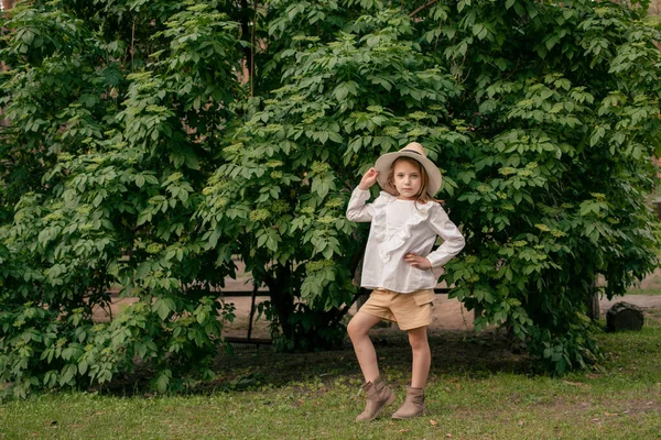 Стильная дочка-подросток, стоящая у зеленого забора в парке в летний день — стоковое фото