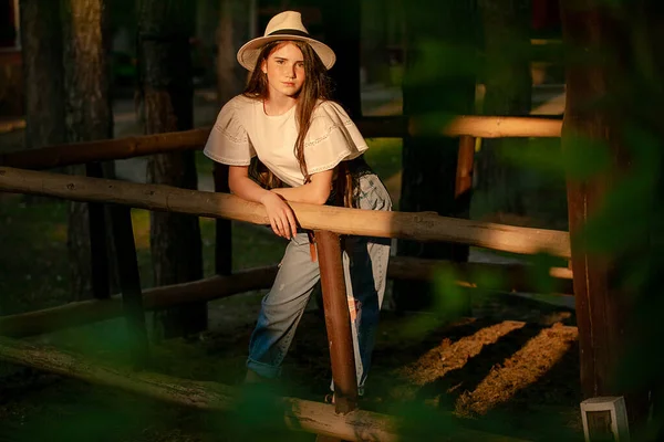 Tinédzser lány áll vidéki birtok erdőben sugarak lenyugvó nyári nap — Stock Fotó