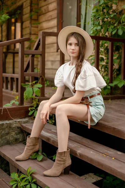 Barna hajú tini lány ül a küszöbén vidéki ház a nyári napon — Stock Fotó