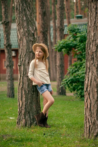 Dromerig tussen een meisje leunend tegen een boom in de groene zomertuin van het landhuis — Stockfoto