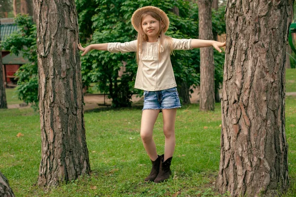 Alegre chica adolescente posando entre dos árboles altos en verde parque de verano — Foto de Stock
