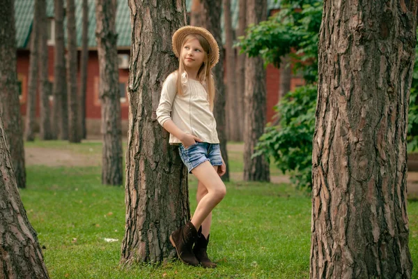 Dromerig tiener meisje leunend tegen hoge boom in groene binnenplaats van landhuis — Stockfoto