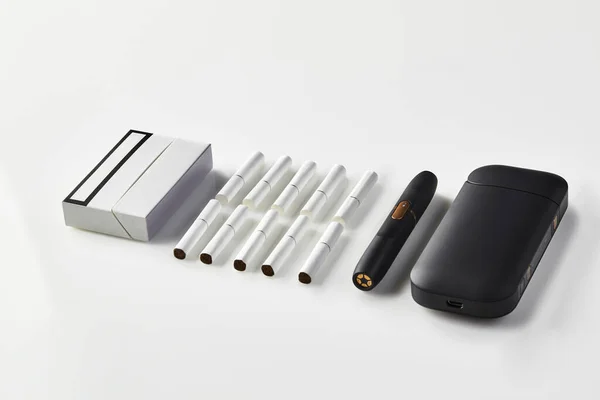 Új generációs fekete elektronikus cigaretta és akkumulátor, csomag és tíz hőnyaláb elszigetelt fehér. Új technológia. Fűtés dohányrendszer. Közelről. — Stock Fotó