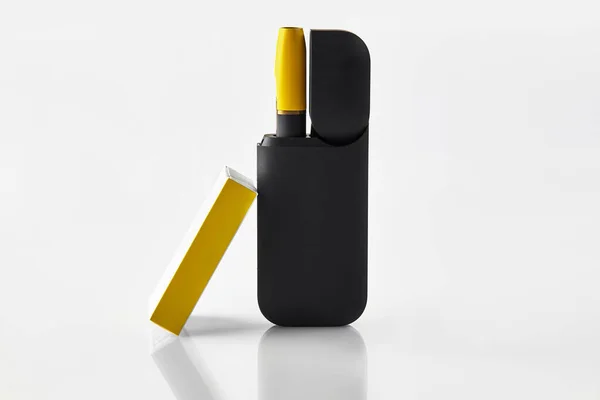 Černá a žlutá elektronická cigareta nové generace v otevřené baterii a krabičce od sirek izolované na bílém. Systém vytápění tabáku. Reklama, zavřít — Stock fotografie