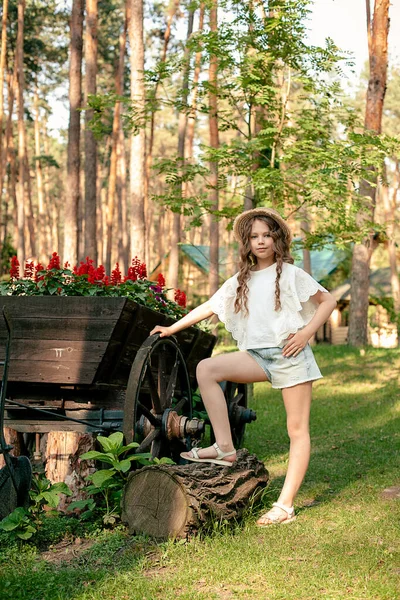 Tween lány pózol mellett virágzó fa kocsi alakú virágágyás a vidéki birtok — Stock Fotó