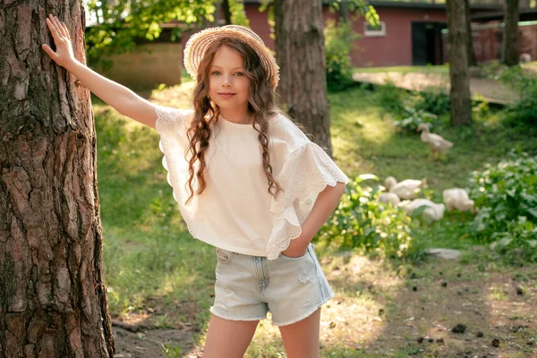 Девочка-подросток облокотилась на ствол высокого дерева в зеленом дворе дачи — стоковое фото