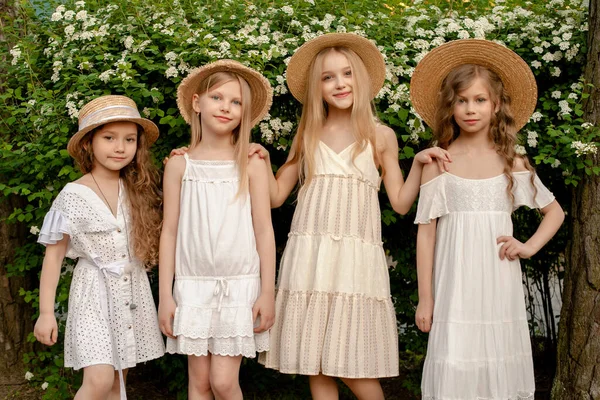 Amistoso niñas preadolescentes felices de pie cerca de grandes arbustos verdes con flores blancas — Foto de Stock