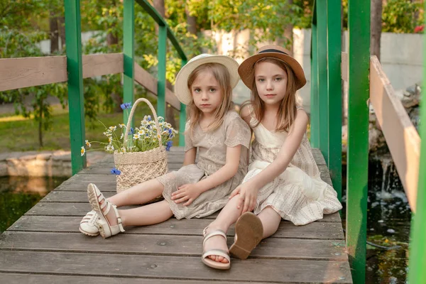 Deux filles de préadolescence assis sur le pont sur l'étang dans la propriété de campagne d'été — Photo