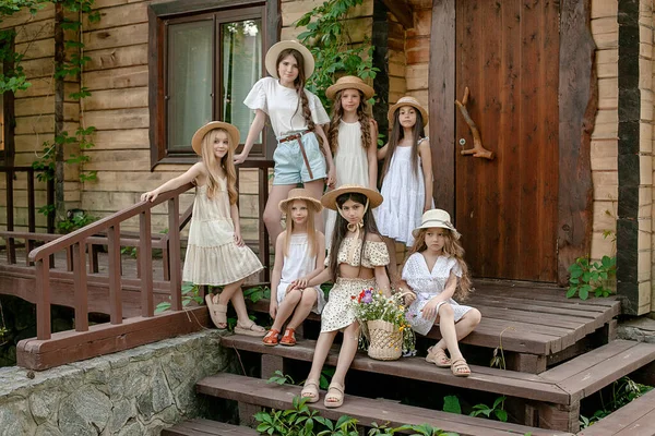 Tbetween meisjes poseren samen op de stoep van houten landhuis in de zomer — Stockfoto