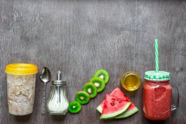 Sağlıklı Kahvaltı: yulaf ezmesi granola, kivi ve karpuz koyu ahşap arka plan üzerinde cam kavanoza taze yüzlü