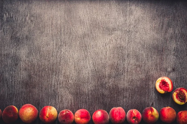 Frutas frescas de melocotones sobre fondo rústico de madera oscura, vista superior. Tonificado — Foto de Stock