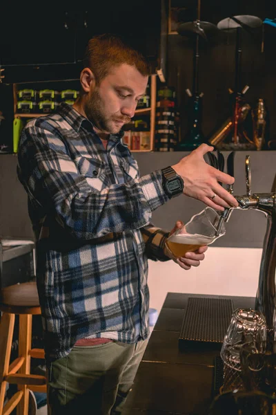 Бородатый бармен наполнения стекла с нефильтрованным пивом из крана в пабе — стоковое фото
