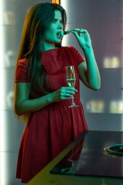 Genç esmer kız evde hafif atıştırmalıklarla şampanyayı seviyor.