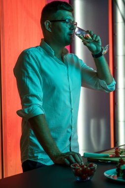 Genç adam evde yemek hazırlarken bir bardak şampanyanın keyfini çıkarıyor.