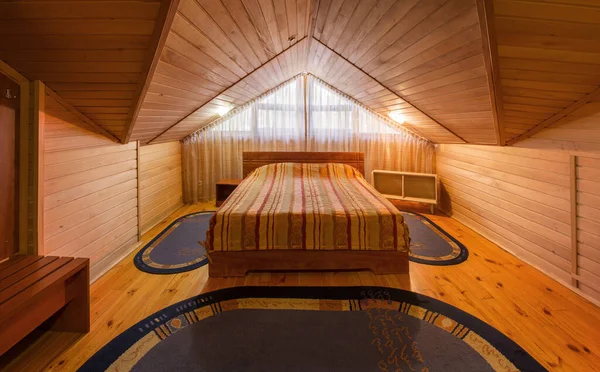 Habitación de hotel Mansard con guarnición de madera natural, cama doble y percha —  Fotos de Stock