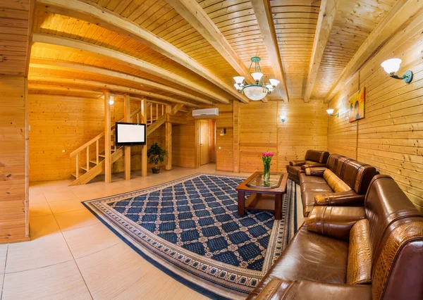 Dom na wsi pokój dzienny z wykończeniem drewna, skórzana sofa, stolik kawowy i TV — Zdjęcie stockowe