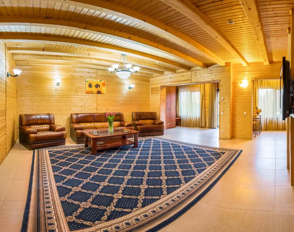Salón en casa de campo con acabados de madera natural, sofá de cuero con sillones y mesa de centro —  Fotos de Stock