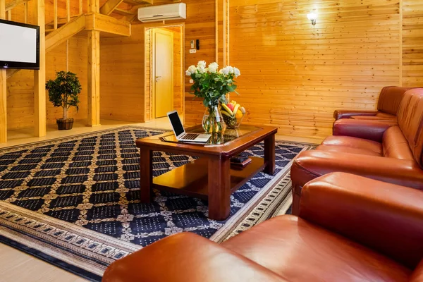 Salon w wiejskim domu z naturalnym wykończeniem drewna, skórzaną sofą i telewizorem — Zdjęcie stockowe