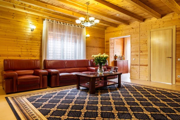 Acogedora sala de estar en casa de campo con acabado de madera natural, sofá de cuero y mesa de centro —  Fotos de Stock