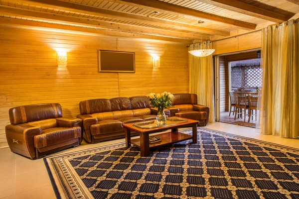 Dom na wsi salon wykończony naturalnym drewnem ze skórzaną sofą i stołem kawowym — Zdjęcie stockowe