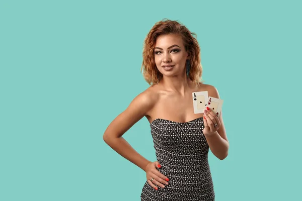 Ginger dívka v šedých šatech je pózování drží dvě hrací karty v rukou stojí na modrém pozadí studia. Kasino, poker. Detailní záběr. — Stock fotografie