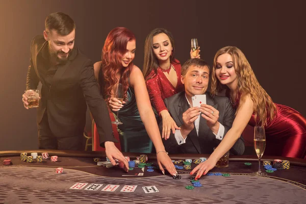 Grupa młodych zamożnych przyjaciół gra w pokera w kasynie. — Zdjęcie stockowe
