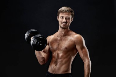 Siyah arka plan üzerine poz dumbbells ile egzersiz bir genç uygun vücut geliştirmeci yatay atış kırpılmış