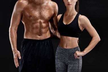 Spor, fitness, egzersiz kavramı. Çift, güçlü kas adam ve siyah bir arka plan üzerinde poz ince kadın uygun