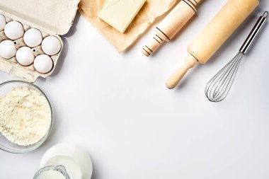 Hamur hazırlığı. Tarifteki malzemelerin miktarının ölçümü. Hamur için malzemeler: un, yumurta, merdane, çırpı, süt, tereyağı, krema. Üst görünüm, metin için boşluk. Devam et