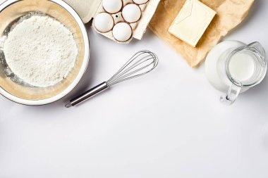 Hamur hazırlığı. Tarifteki malzemelerin miktarının ölçümü. Hamur için malzemeler: un, yumurta, merdane, çırpı, süt, tereyağı, krema. Üst görünüm, metin için boşluk. Devam et