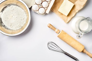 Hamur hazırlığı. Tarifteki malzemelerin miktarının ölçümü. Hamur için malzemeler: un, yumurta, merdane, çırpı, süt, tereyağı, krema. Üst görünüm, metin için boşluk. Devam et