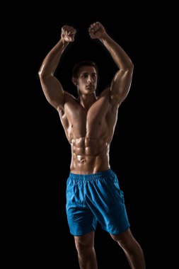 Kas ve uygun genç vücut geliştirmeci fitness erkek modeli siyah arka plan üzerinde poz. Siyah arka planda stüdyo çekimi.