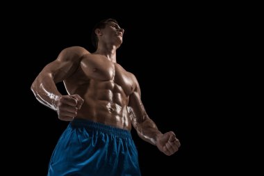 Kas ve uygun genç vücut geliştirmeci fitness erkek modeli siyah arka plan üzerinde poz. Siyah arka planda stüdyo çekimi.