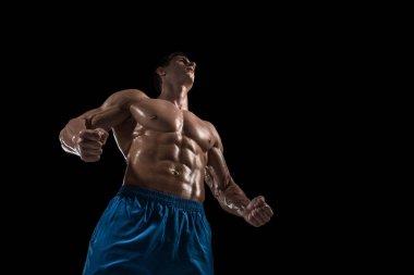 Kas ve uygun genç vücut geliştirmeci fitness erkek modeli siyah arka plan üzerinde poz. Siyah arka planda stüdyo çekimi.