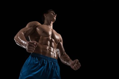 Kas ve uygun genç vücut geliştirmeci fitness erkek modeli siyah arka plan üzerinde poz. Siyah arka planda stüdyo çekimi.