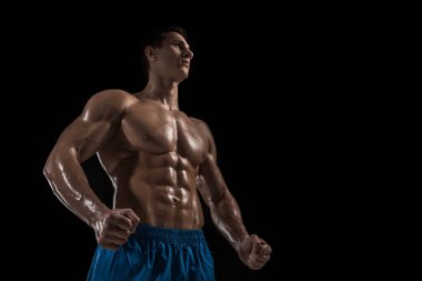 Kas ve uygun genç vücut geliştirmeci fitness erkek modeli siyah arka plan üzerinde poz. Siyah arka planda stüdyo çekimi.