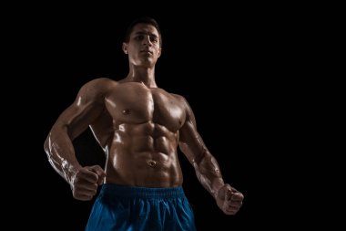 Kas ve uygun genç vücut geliştirmeci fitness erkek modeli siyah arka plan üzerinde poz. Siyah arka planda stüdyo çekimi.
