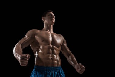 Kas ve uygun genç vücut geliştirmeci fitness erkek modeli siyah arka plan üzerinde poz. Siyah arka planda stüdyo çekimi.