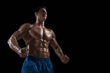 Kas ve uygun genç vücut geliştirmeci fitness erkek modeli siyah arka plan üzerinde poz. Siyah arka planda stüdyo çekimi.